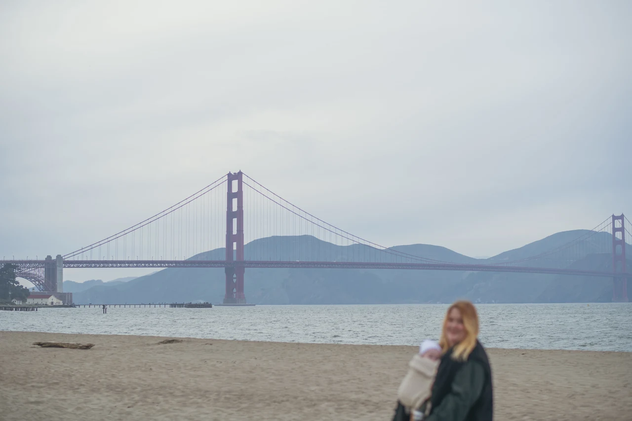 A person on the beach with the Golden Gate Bridge in the background.